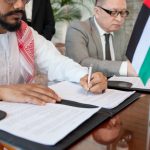 Young bearded Arabian businessman signing contract of business partnership