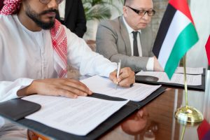 Young bearded Arabian businessman signing contract of business partnership