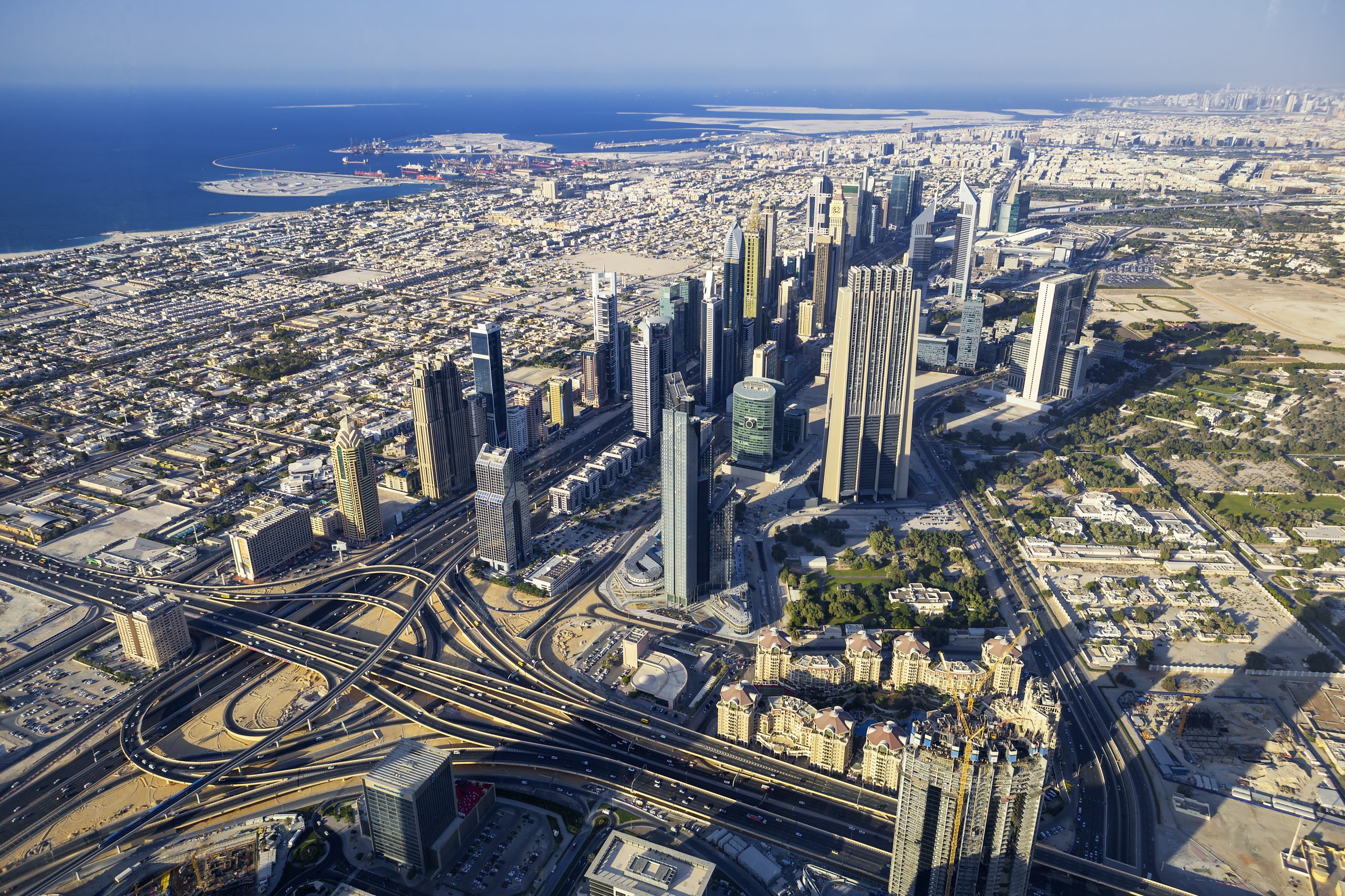 Aerial view of Dubai's sprawling urban landscape and complex road networks, illustrating the city's ongoing development.